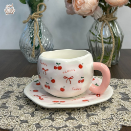 طقم كوب سيراميك فاخر مع طبق بتصميم "سويت كرز" الكوري ومقبض وردي Premium Ceramic Cup and Saucer Set with Cherry & Ribbon Pattern